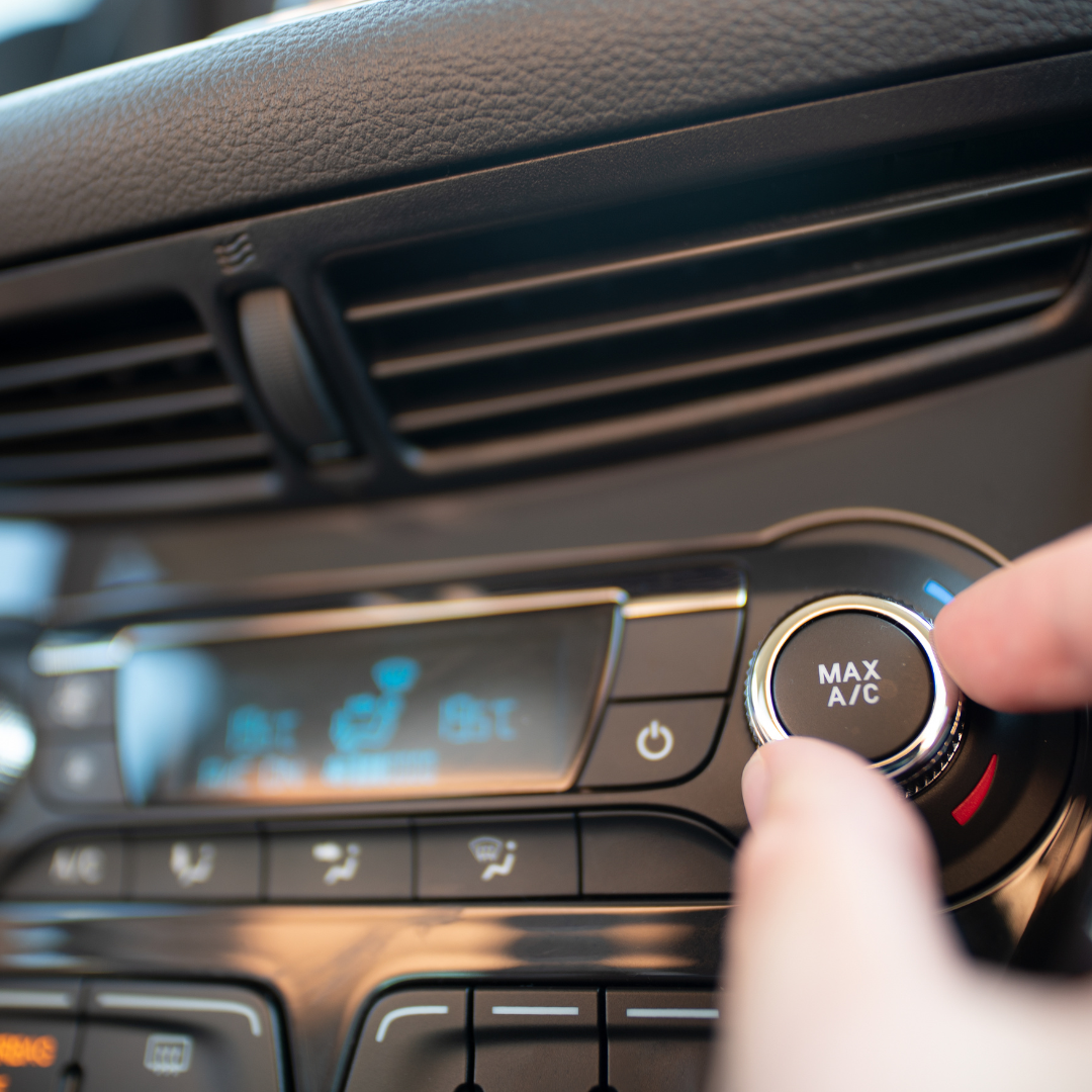 photo of vehicle's dash with fingers turning the air conditioning knob